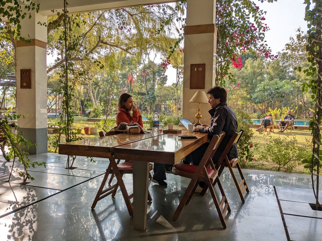 A guest working at a table under bougainvillea — PushkarOrganic